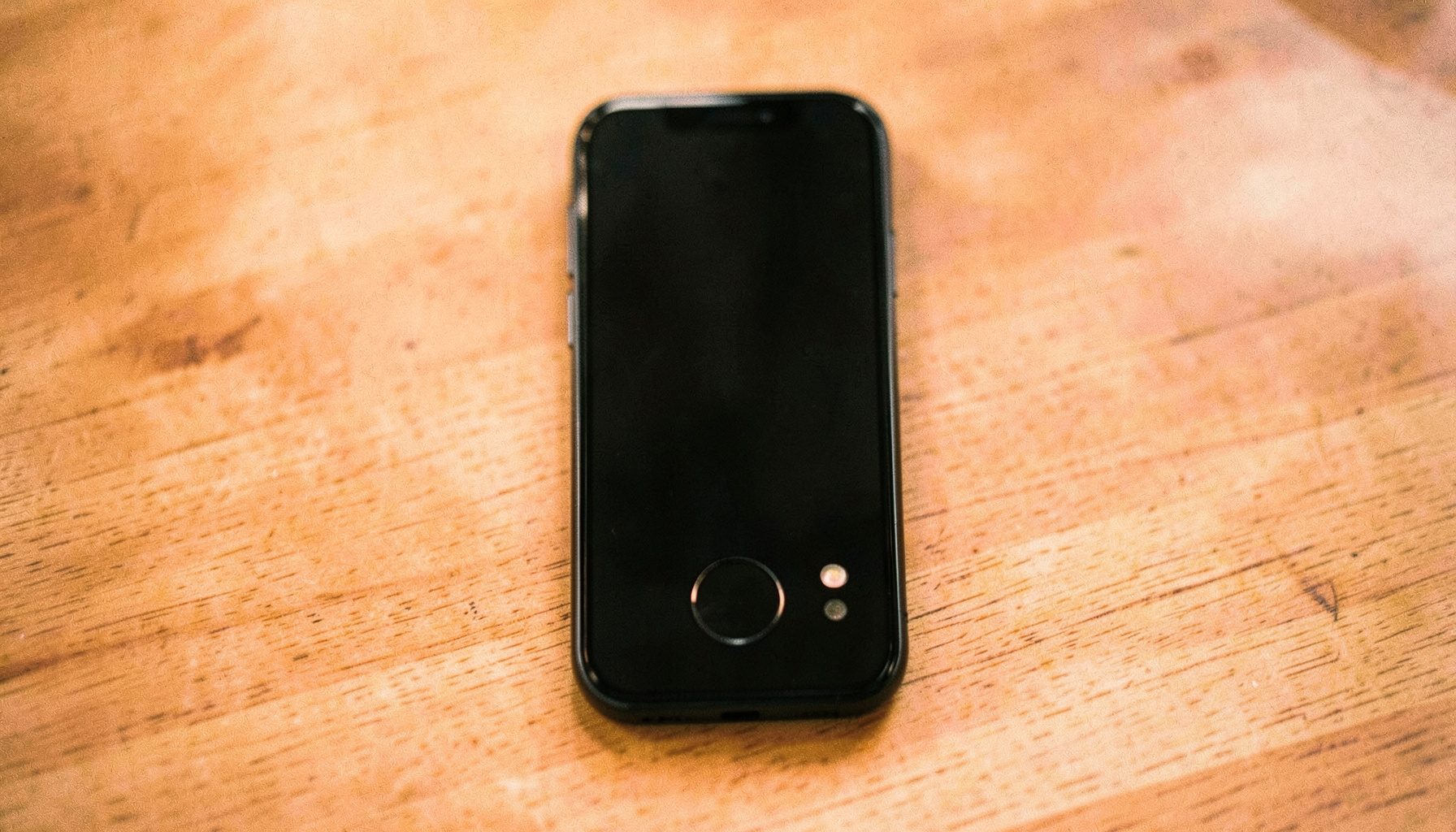 Jio F61F klahvistikuga telefon laual, ekraanil taaste režiimi indikaator. Domineerivad mustad ja hallid toonid.